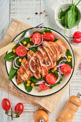 Chicken fillet with salad spinach, cherry tomatoes, cornflower and onion. Healthy food. Keto diet, diet lunch concept. Top view on white background.