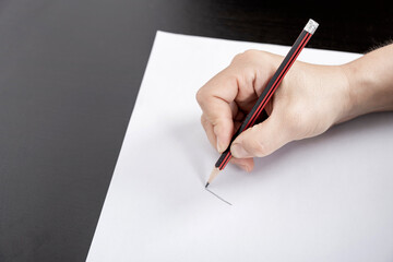 A woman's hand writes on a blank piece of paper