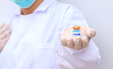 Close up Asian doctor, scientist, wearing gloves, holding a Vaccine, syringe