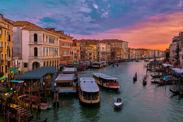Fototapeta na wymiar Sunset view of Grand Canal, Venice, Italy. Vaporetto or waterbus station, boats, gondolas moored by walkways, beautiful sunset clouds, UNESCO heritage