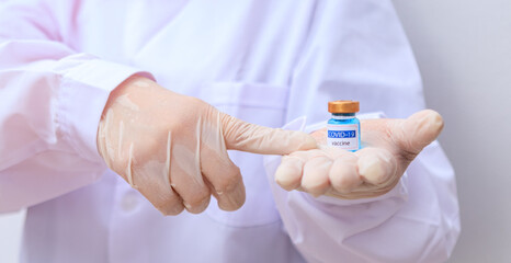 Obraz premium Close up Asian doctor, scientist, wearing gloves, holding a Vaccine, syringe