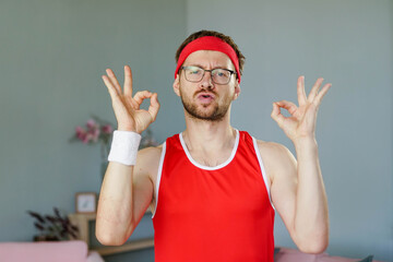 Fototapeta premium Portrait of funny sportsman in red sportswear making OK sign on