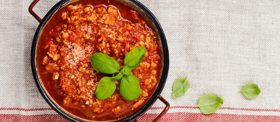 Traditional italian Bolognese sauce in saucepot an old dark wooden background. Top view, copy space