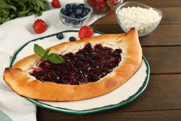Delicious sweet cottage cheese pastry with cherry jam on wooden table