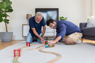 Senior father and adult son playing with toy wooden together at home with happy and smile. Two men...