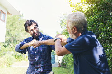 Senior father and adult son playing together in the garden with happy and fun