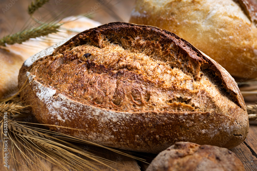Poster bakery background. set of freshly baked crispy bread and buns with ears of wheat on wooden table wit