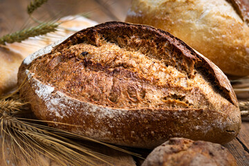 Bakery background. Set of freshly baked crispy bread and buns with ears of wheat on wooden table with copy space