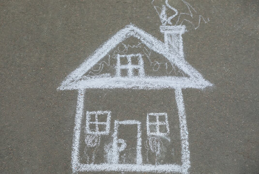 Child's chalk drawing of house on asphalt, top view