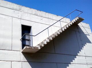 Exterior staircase with railing leading to the rooftop of an industrial building