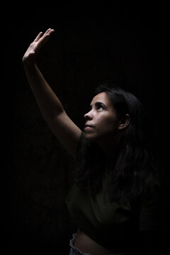 Eautiful Young Caucasian Female Blocking The Light With Her Hand On A Dark Background