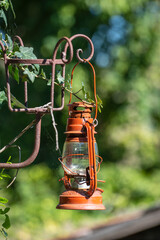 A single old red kerosene lantern hanging against a garden background, Hungary