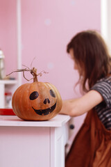 Halloween pumpkin on wooden table in schoolgirls room. child girl on backgroung doing homework