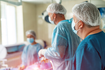 Obraz premium Modern clinic. Hospital with team of doctors standing and discussing something. Doctors are operating with medical tools. Back view