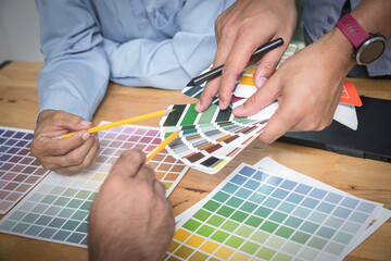 Fototapeta na wymiar Interior designer chooses a color chart for home design. Graphic designers working on color chart at modern office.