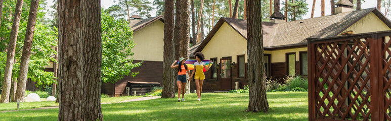Interracial lesbian couple running with lgbt flag outdoors, banner.