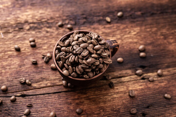 Coffee beans in a clay cup on a brown wooden old background.