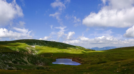 Fototapeta na wymiar little wonderful pond in the green mountain landscape with blue sky panorama