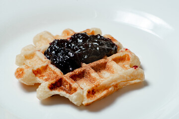 Belgian waffles with blueberry or blackcurrant jam close-up.