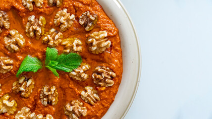 Red Muhammara close-up on table. horizontal top view , hot pepper dip originally from Syria, Lebanon.