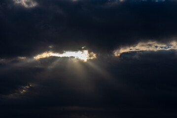 Naklejka na ściany i meble Rays of light shining throug dark clouds.Beautiful dramatic sky with sun rays.
