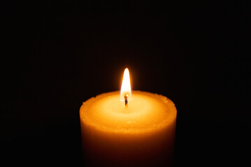 One single light candle burning brightly in the black background.Spiritual candle yellow flame. Flame of candle in the darkness.Copy space.
