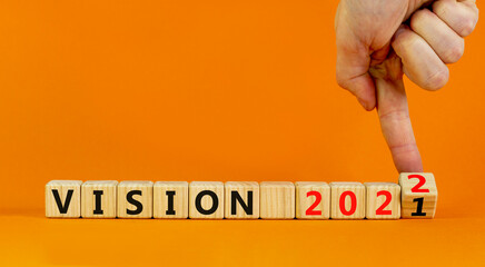 2022 vision new year symbol. Businessman turns wooden cubes and changes words 'vision 2021' to 'vision 2022'. Beautiful orange background, copy space. Business, 2022 vision new year concept.