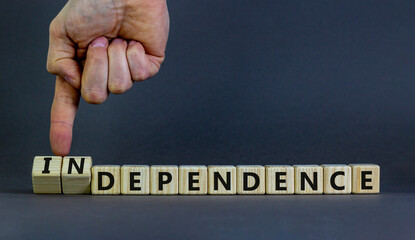 Dependence or independence symbol. Businessman turns cubes and changes the word 'dependence' to 'independence'. Beautiful grey background, copy space. Business, dependence or independence concept.