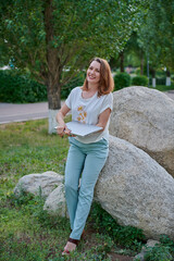 woman in trousers on the lawn with laptop