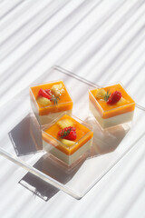 Tropical Fruit Panna Cotta, in square shot glasses, on white background.
