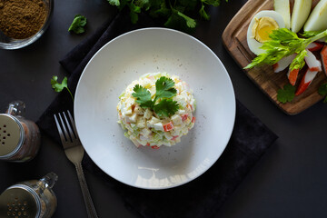 Crab salad with eggs, apple, crab sticks, celery seasoned with mayonnaise and spices on a white plate, horizontal, rustic, top view