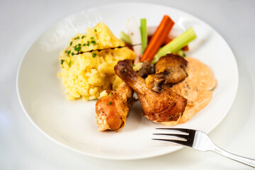 Chicken thig, mashed potato, olive mayonnaise and vegetable on white plate.