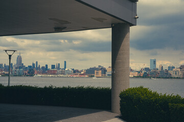 View of Manhattan skyline from underneath building cantilever with columns. 