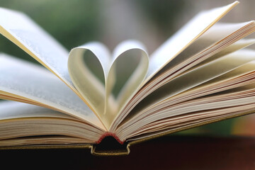 Vintage book with pages shaped like heart. Selective focus.