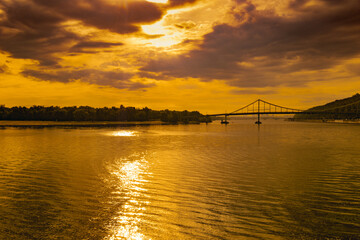 Obraz premium Wide river and distant bridge during sunset