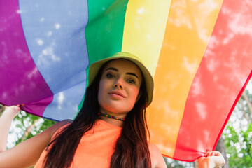Low angle view of young woman holding lgbt flag outdoors.