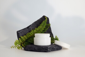 Unbranded natural cosmetic cream packaging standing on stone podium. Cream presentation on the...