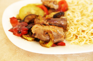 spaghetti with meat and vegetables on a white plate, close-up