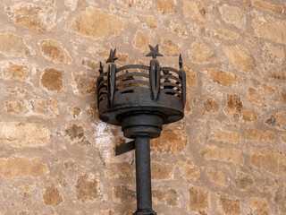 A closeup of a black wrought iron black torch on a stone wall