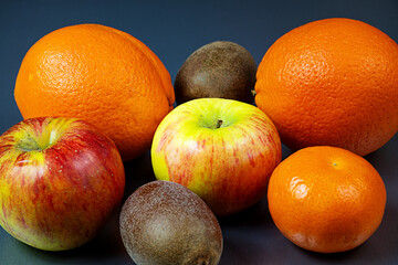 Some apples, kiwi and oranges are next to each other.