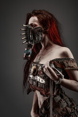Attractive young woman with red eyes wearing post apocalyptic clothing and a gas mask