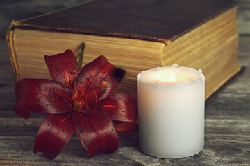 White candle, dark lily flower and closed book. Condolence card
