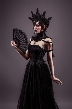 Attractive young woman wearing a black dress, a crown and a fan