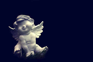 Smiling angel sitting in the grass. Background with a happy angel and copy space