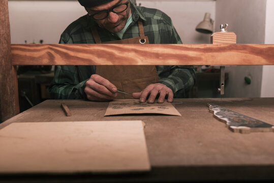 Cabinetmaker working on a wooden ornament in workshop.