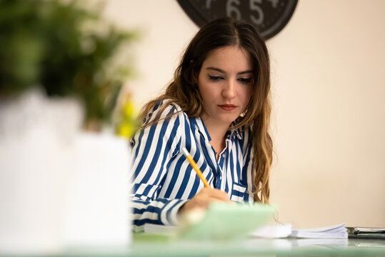 Office girl taking some notes in a notebook at her work table with a p
