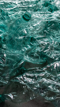 Pile of smashed plastic bottles laying on the floor one bottle up