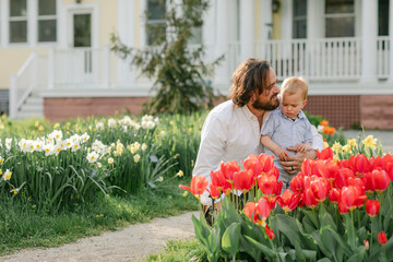 Father teaching toddler son about flowers in tulip garden