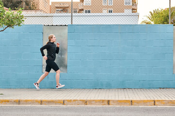 Young woman in sportswear runs through the city