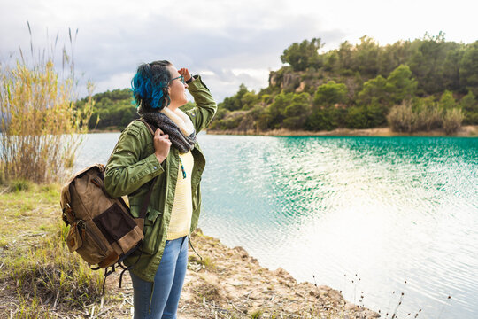 Enlightened female traveler contemplating beautiful lake at sunrise